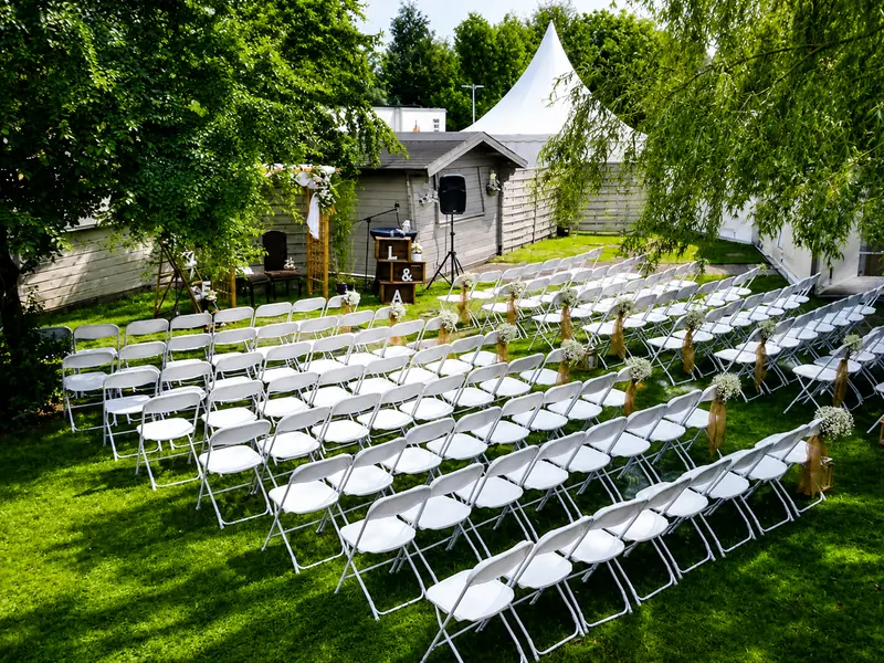 Cérémonie de mariage en extérieur avec rangées de chaises blanches PackEvent et arche fleurie en Loire-Atlantique
