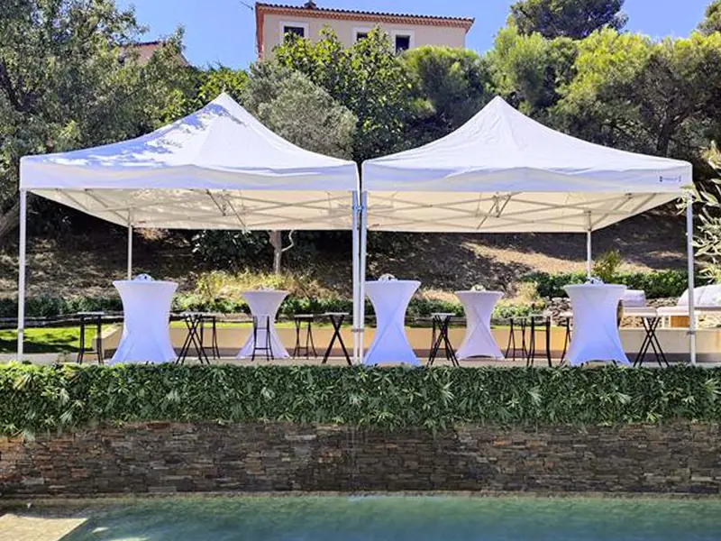 Deux barnums blancs PackEvent installés devant une piscine avec mange-debout pour une réception estivale
